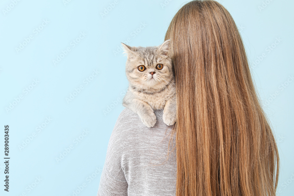 Beautiful young woman with cute cat on color background