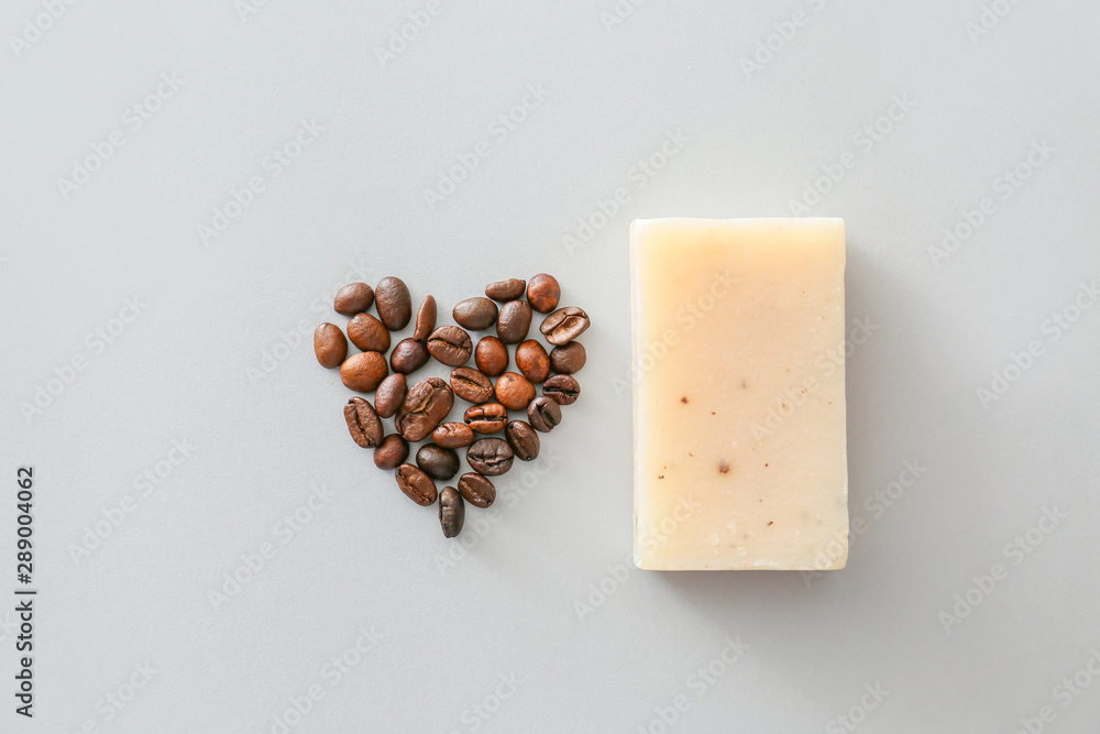 Soap with heart shape made of coffee beans on grey background