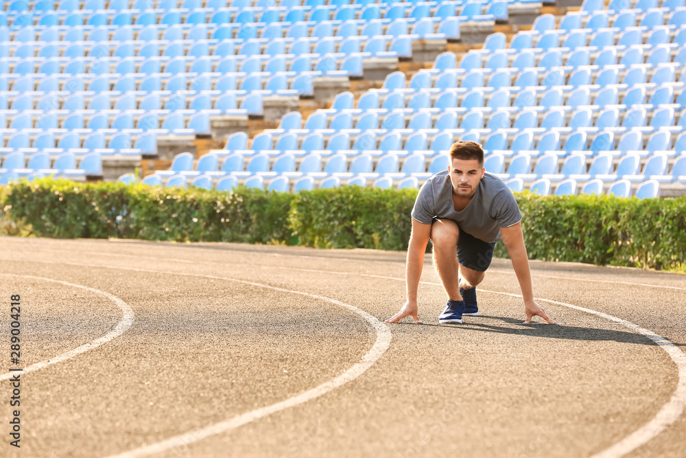 Sporty man in crouch start position at the stadium