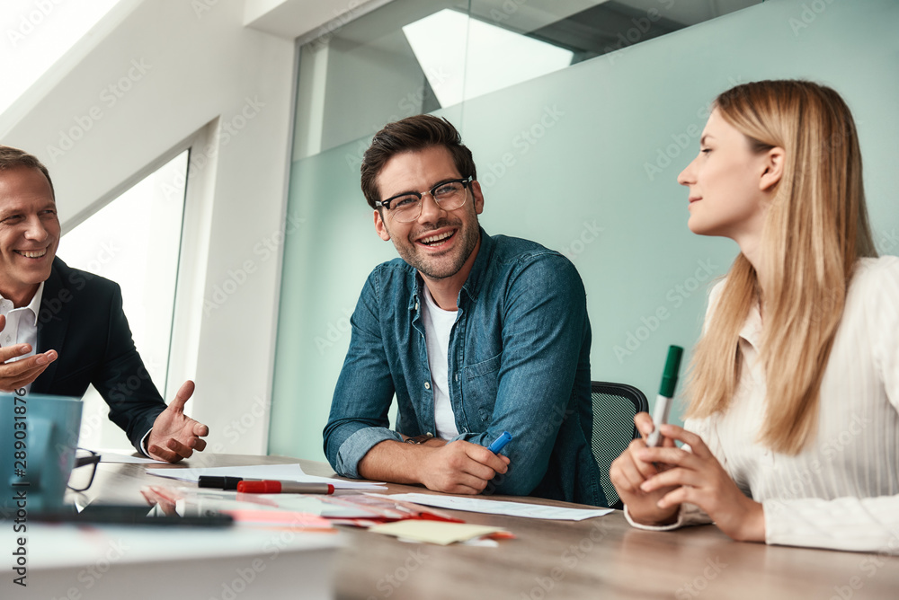 We have great results Young handsome man in eyeglasses discussing something with colleagues and smil