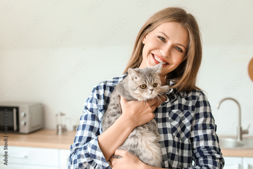 美丽的年轻女人和可爱的猫在厨房