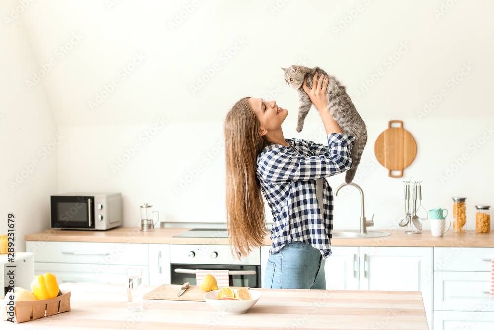 美丽的年轻女人和可爱的猫在厨房