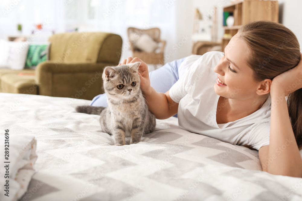 漂亮的年轻女人和可爱的猫在卧室