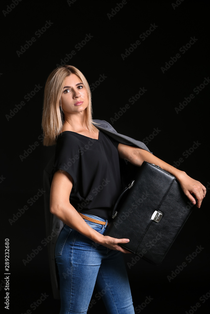 Beautiful stylish businesswoman with briefcase on dark background