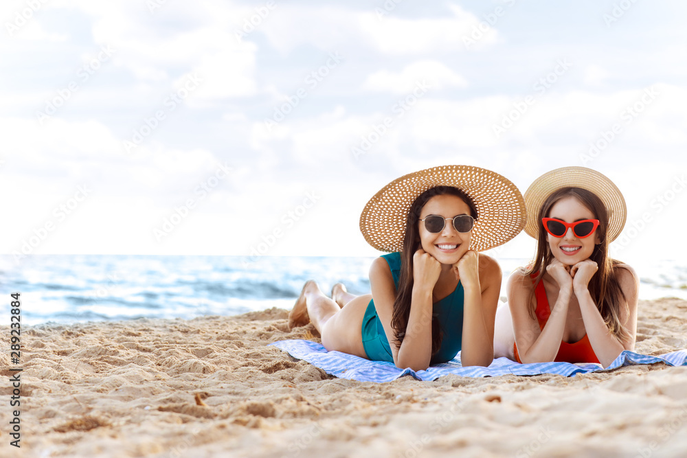 Beautiful young women lying on sea beach at resort