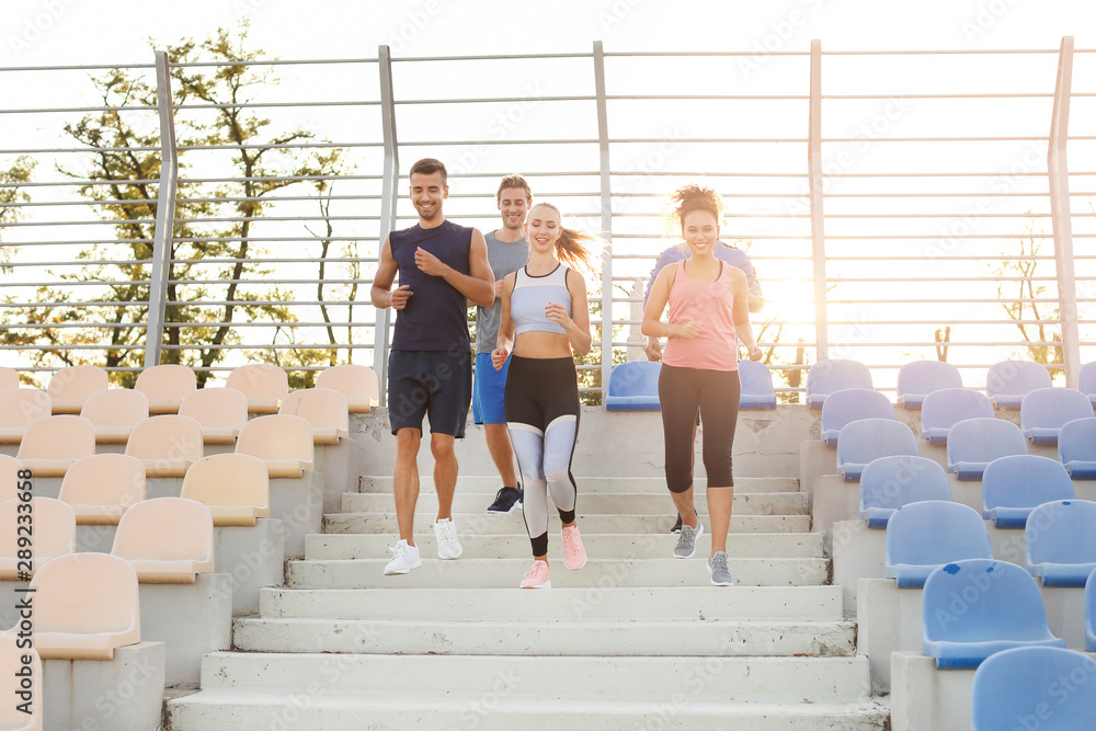 Group of sporty young people training at the stadium