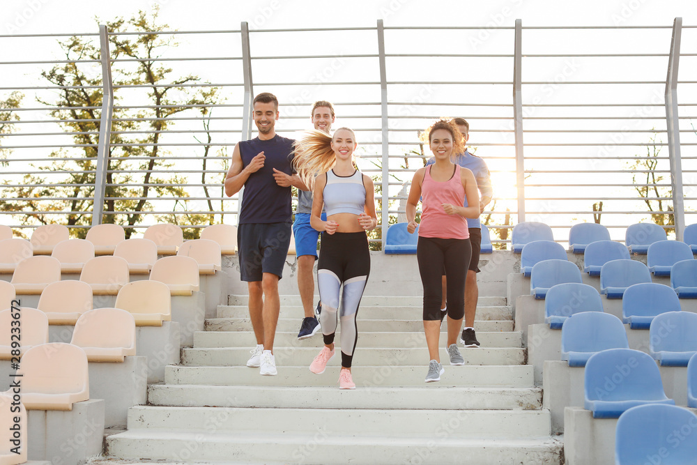 Group of sporty young people training at the stadium