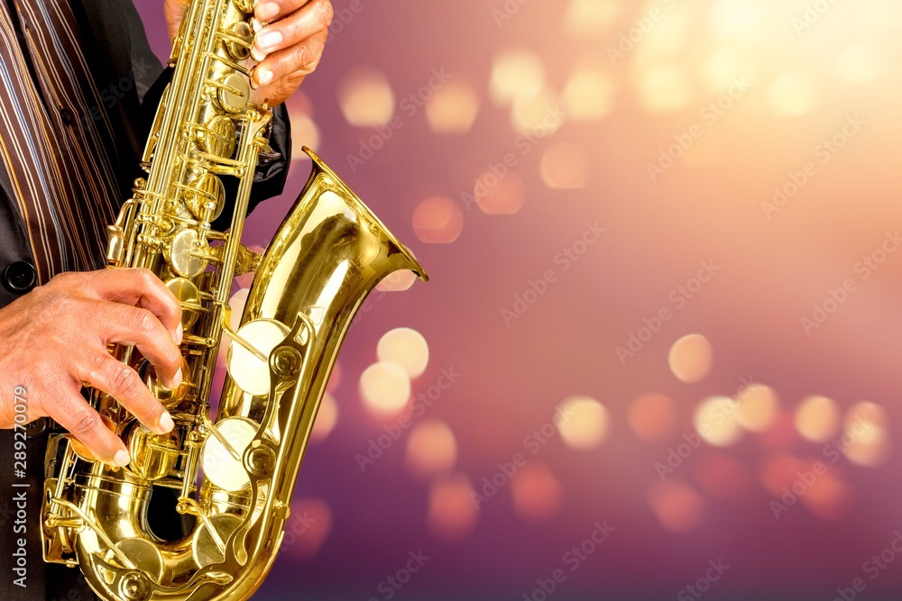 Close-up man playing on saxophone on blurred background