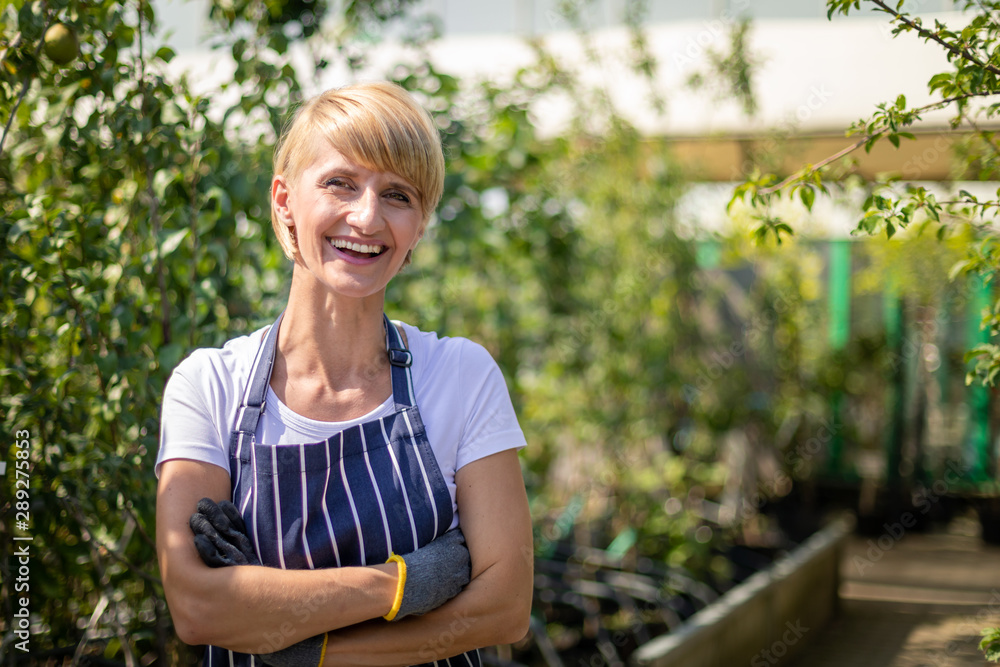 Smiling gardener woman who is employee in garden center