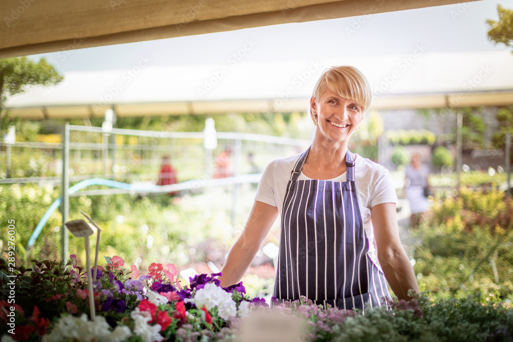 Smiling gardener woman who is employee in garden center