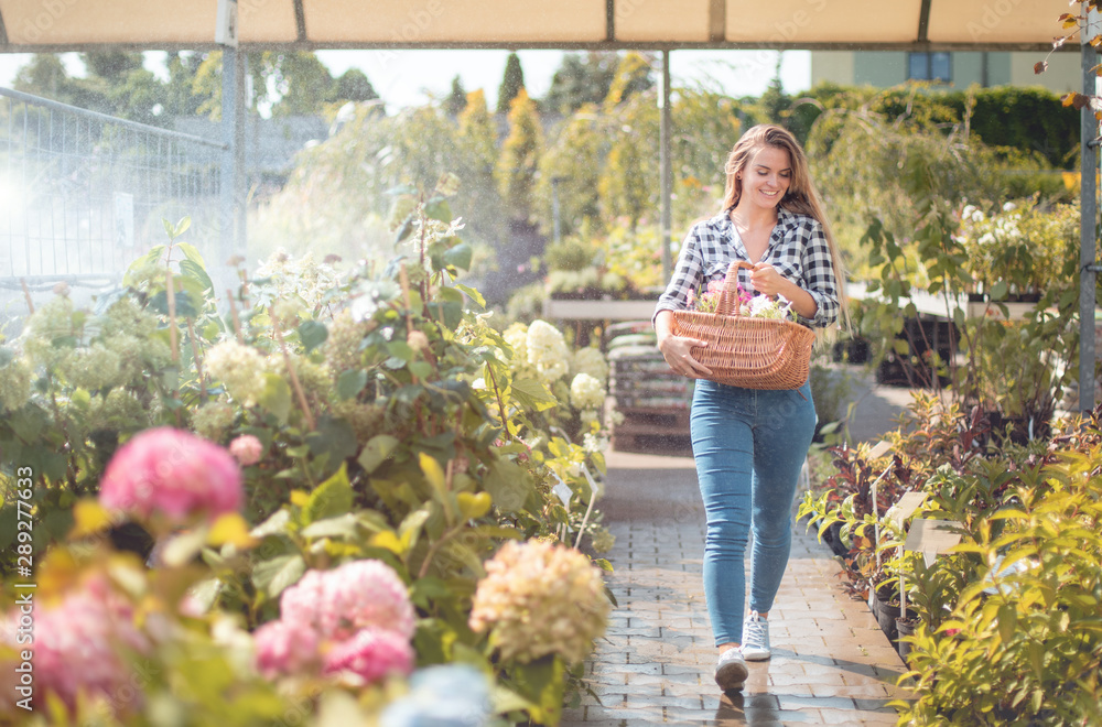 Smiling customer walking along path in garden center between rows of plants