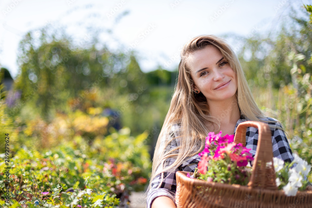 Happy customer in garden center holding basket with flowers