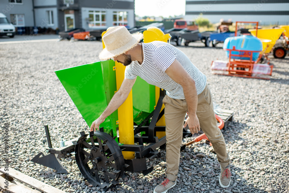 Agronomist choosing a new planter for farming at the outdoor ground of the shop with agricultural ma