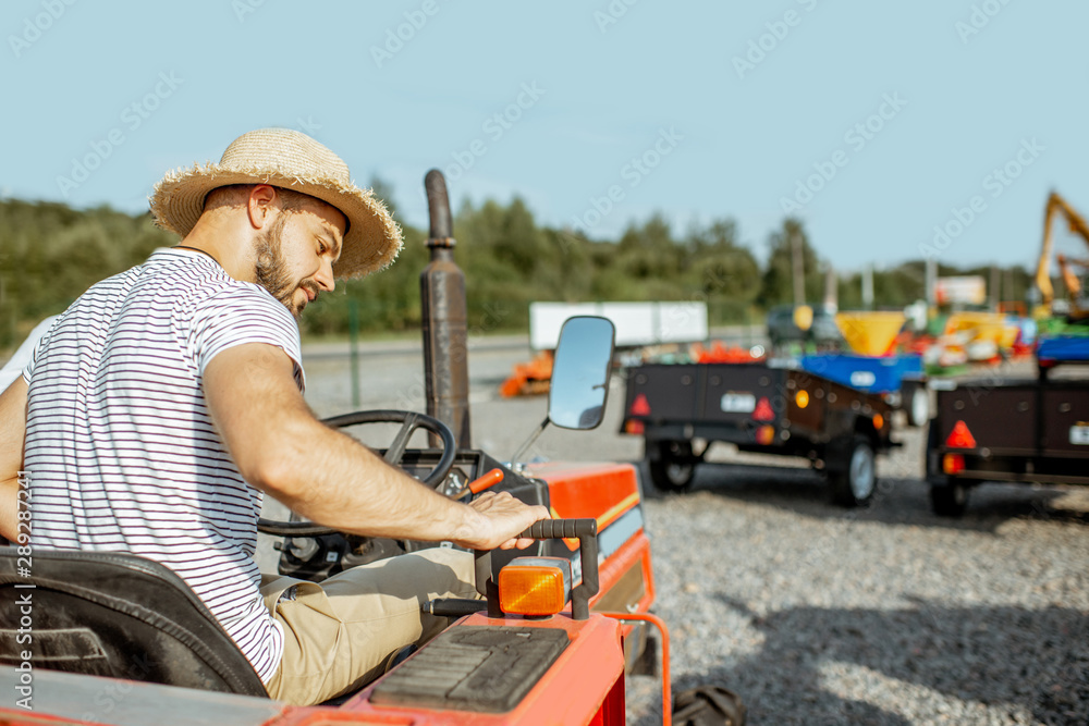 Young agronomist with elegant salesman choosing a tractor for farming on the open ground of agricult