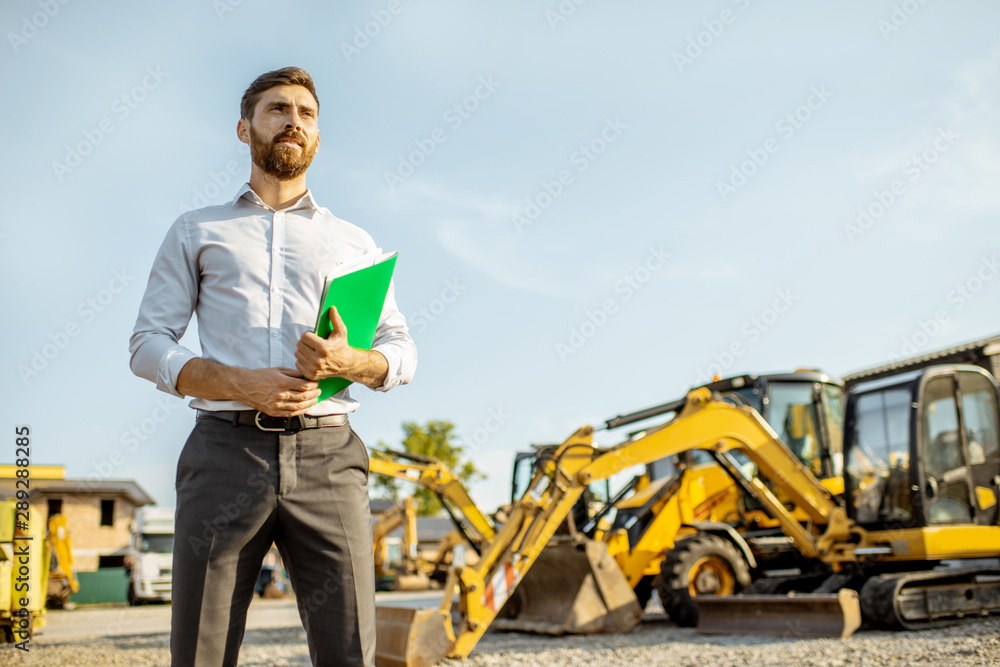 Portrait of a handsome sales consultant or manager standing on the open ground of the shop with heav