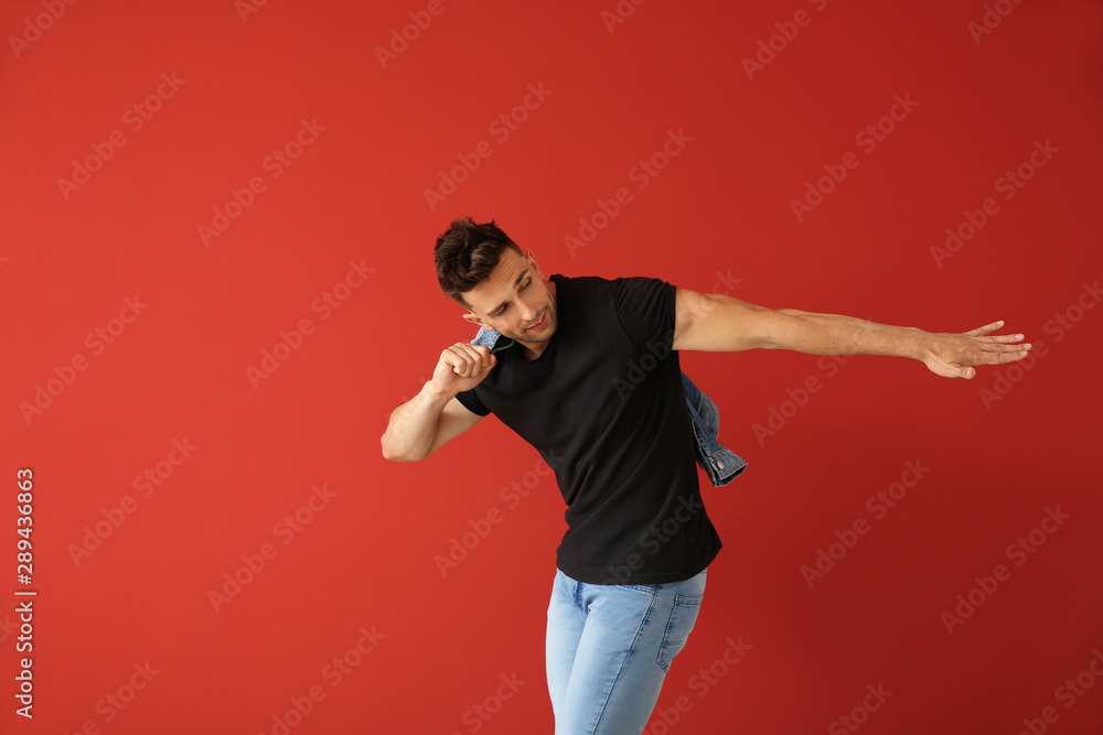 Handsome young man dancing against color background