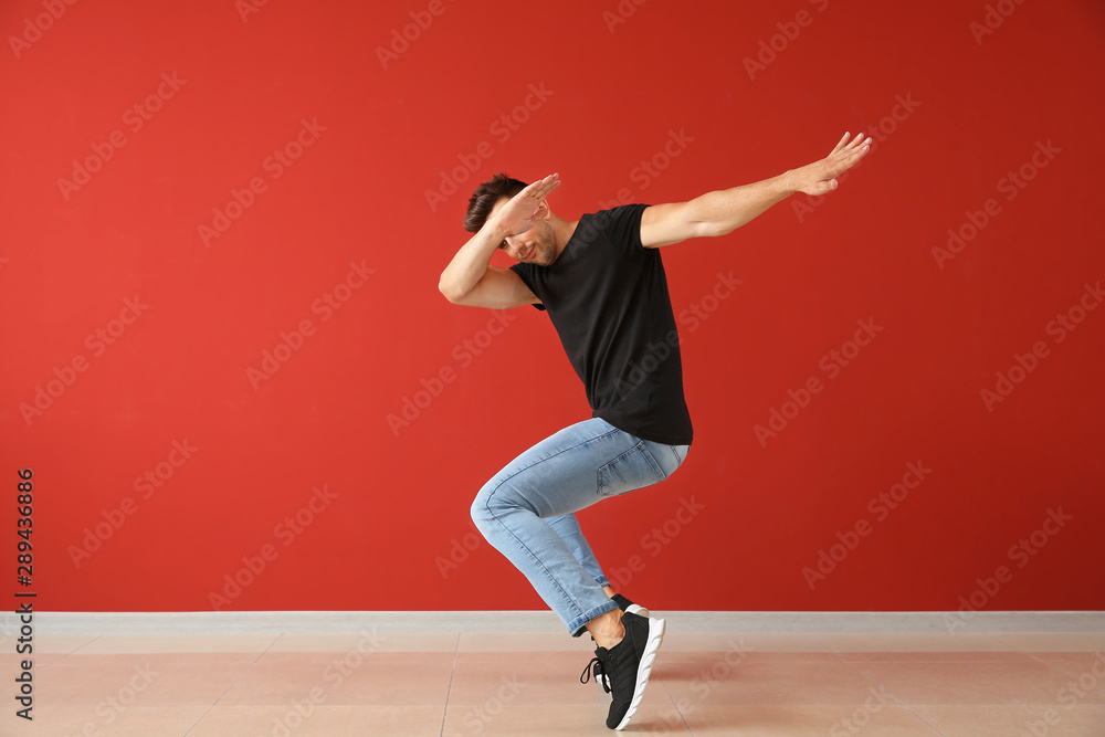 Handsome young man dancing against color wall