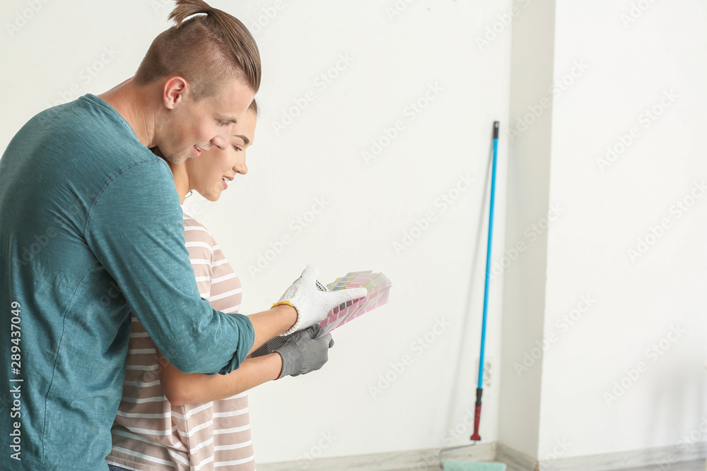 Happy young couple choosing color of walls in their new house