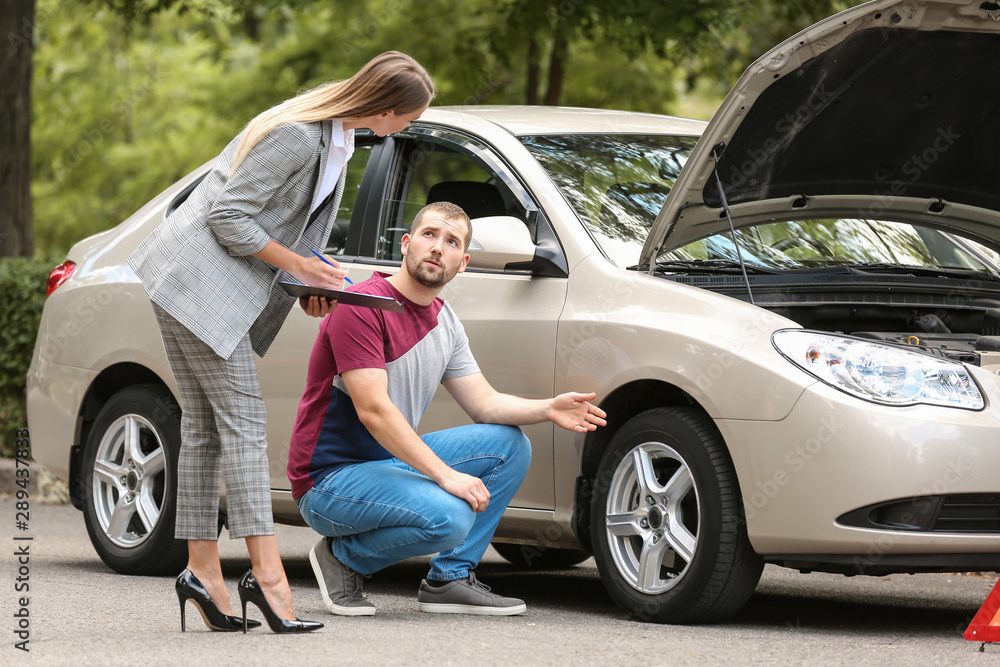 Young man and insurance agent near damaged car outdoors