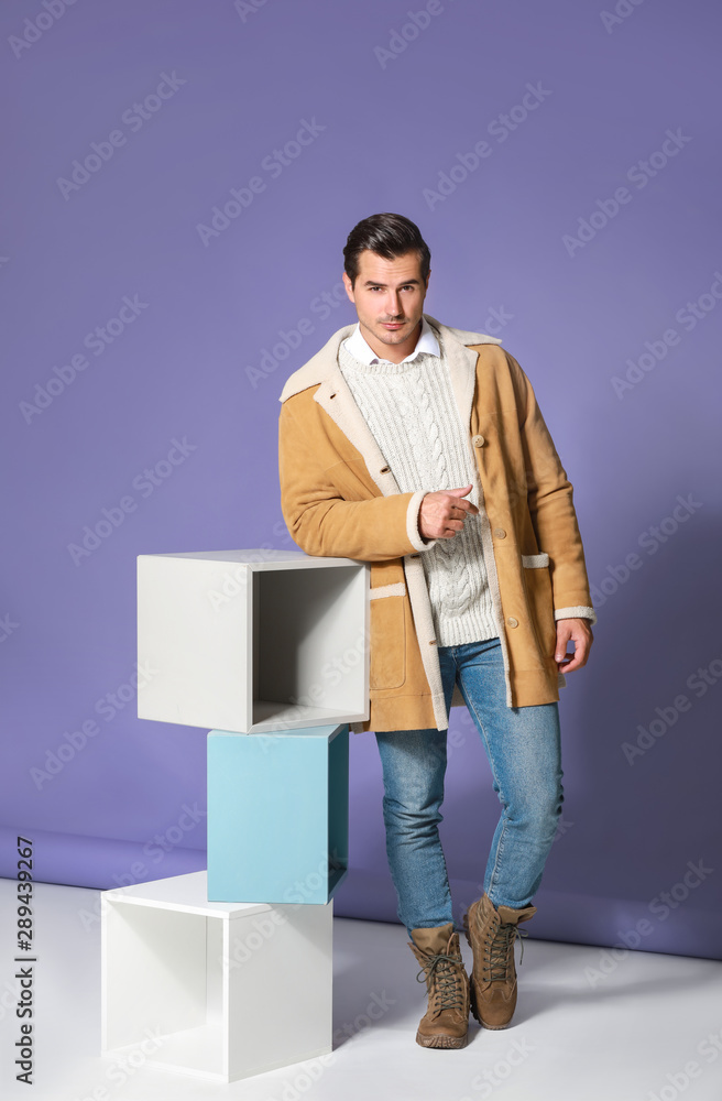 Fashionable man in warm clothes on color background