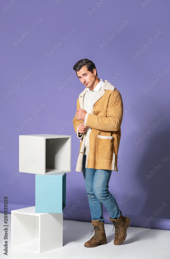 Fashionable man in warm clothes on color background