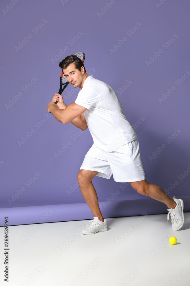 Handsome man playing tennis on color background