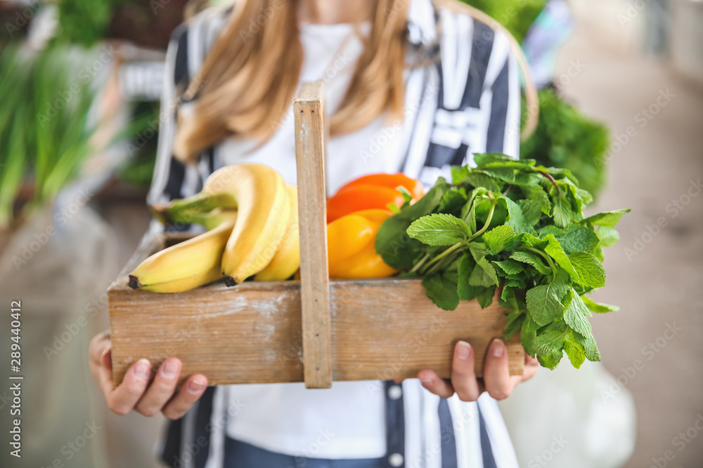 Woman with fresh fruits and vegetables in basket at market, closeup