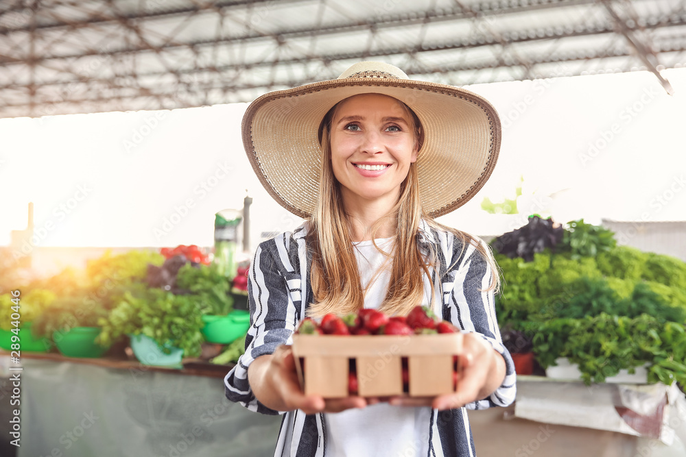 Woman with fresh strawberries in basket at market