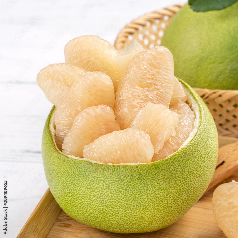 Fresh peeled pomelo, pummelo, grapefruit, shaddock on bright wooden table background. Seasonal fruit