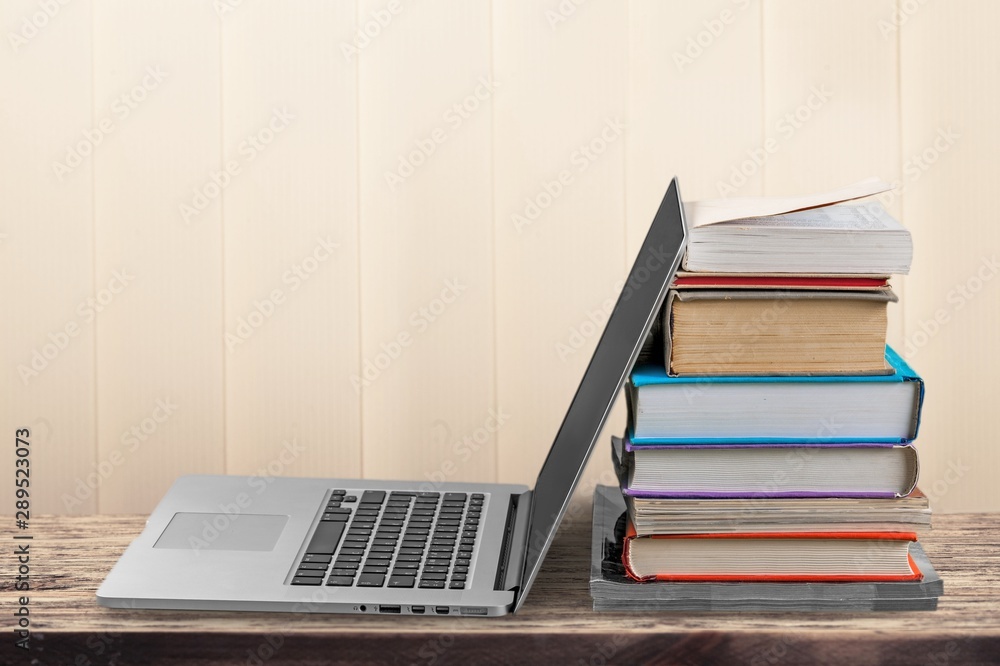 Stack of books with laptop on table