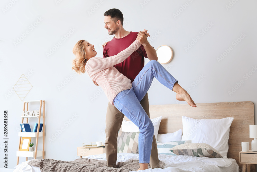 Happy dancing couple in bedroom