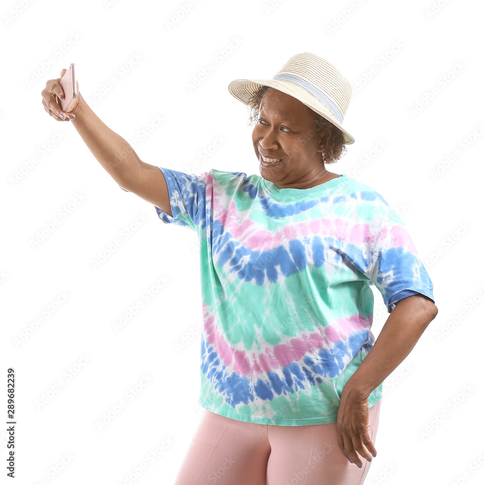 Portrait of African-American woman taking selfie on white background