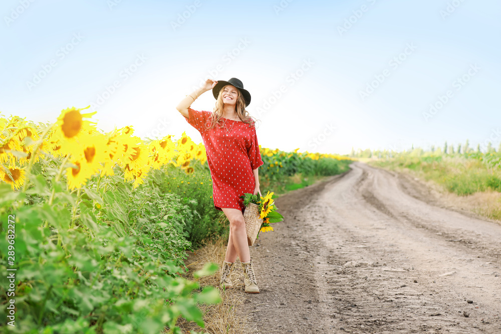 美丽的年轻女子，带着一束向日葵在乡村