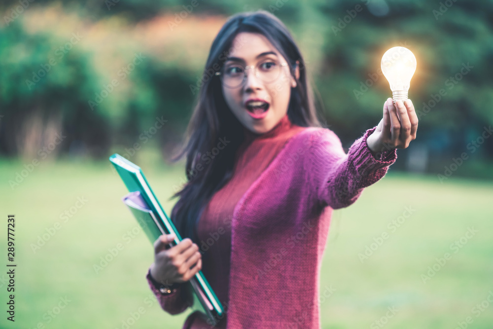 Creative young woman hold shinning light bulb. Concept of knowledge, intelligence and inspiration.