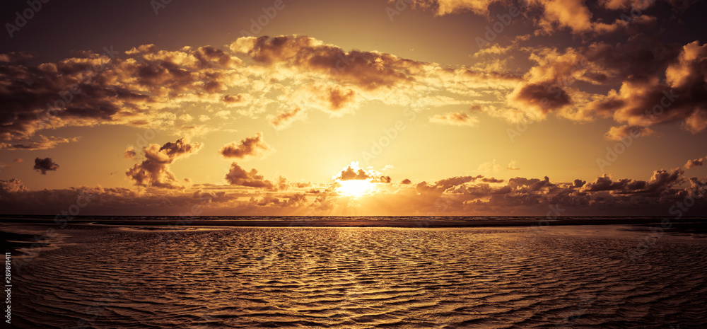 Schöner Sonnenuntergang am Meer mit Wolken und Wasserspiegelung