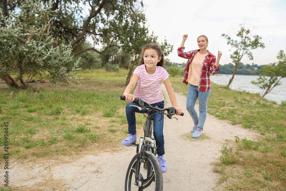 Mother proud of her daughter who learned to ride bicycle outdoors