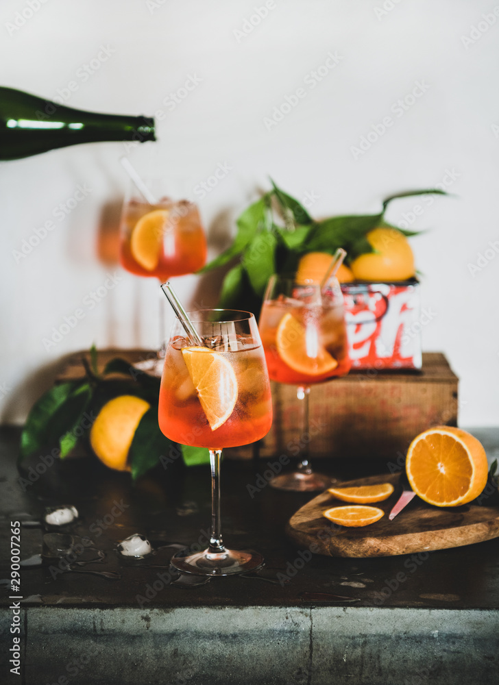 Aperol雪碧开胃酒酒精冷饮，装在玻璃杯里，混凝土桌子上放着橙子和冰块，w