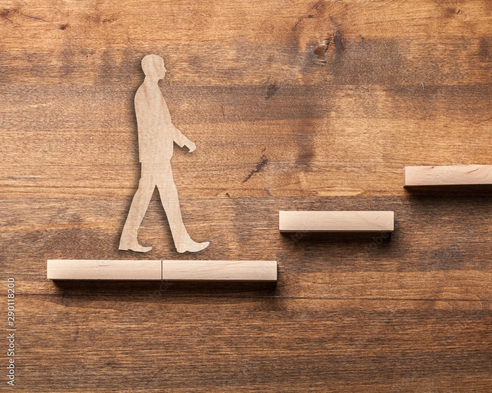 Success concept with wooden businessman climbing wooden block stairs