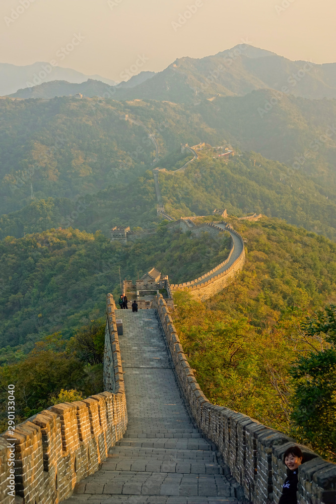 Empty walkway atop the Great Wall running across the vast green mountains.