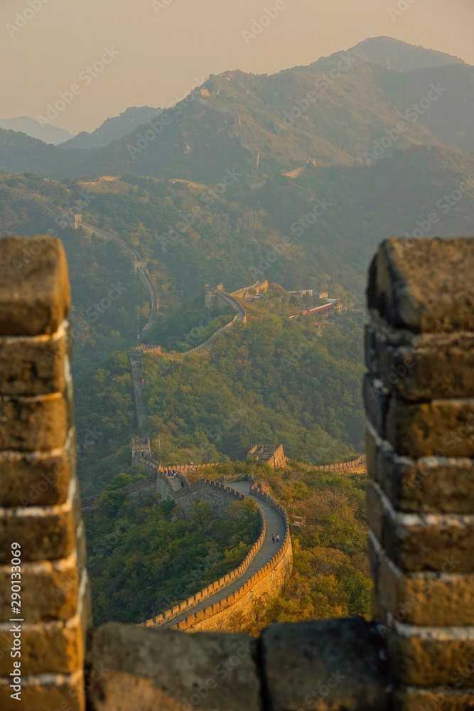 CLOSE UP: Monumental stone wall crosses the forest covered mountains in China.