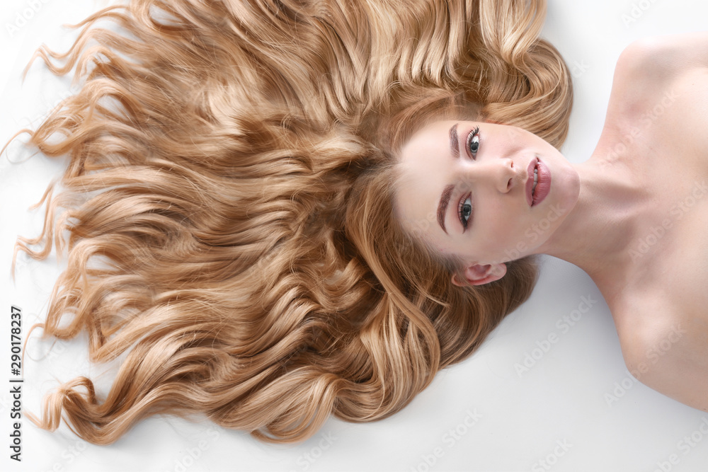 Young woman with beautiful curly hair on light background