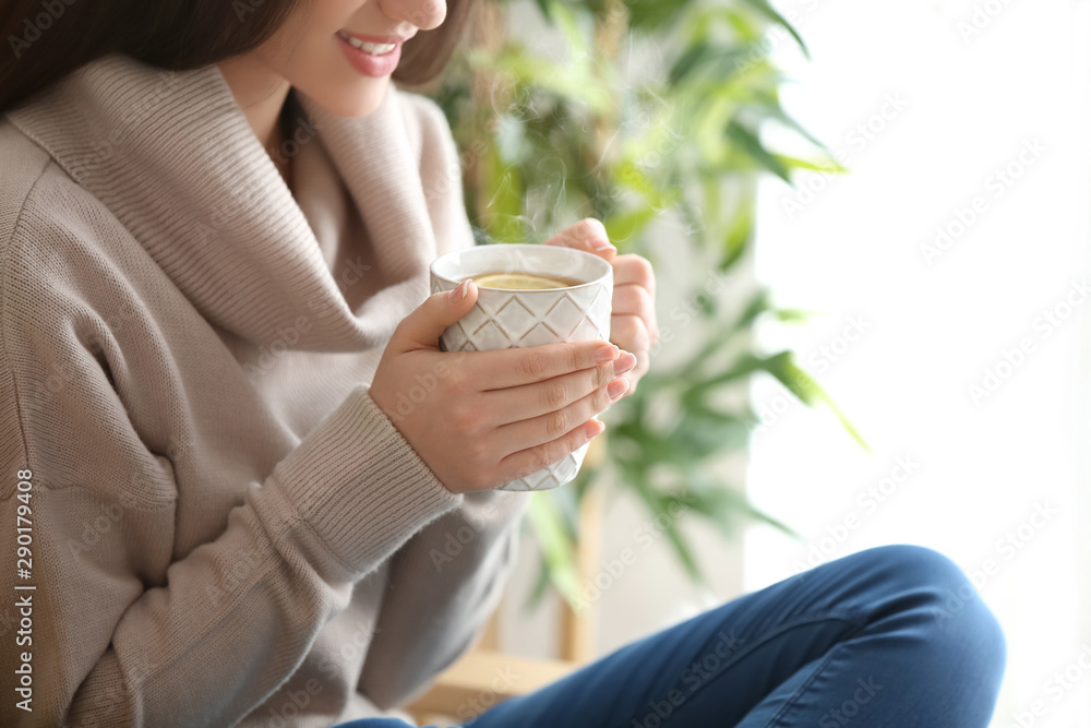 家里有一杯热茶的漂亮年轻女人