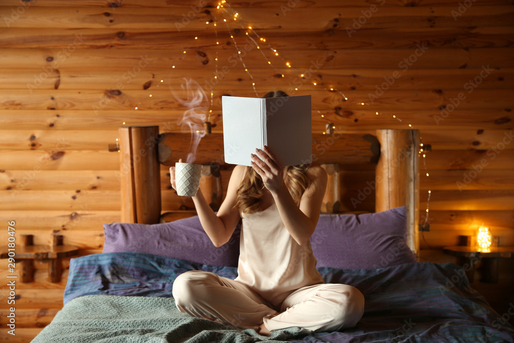 Beautiful woman reading book and drinking coffee in morning at winter resort