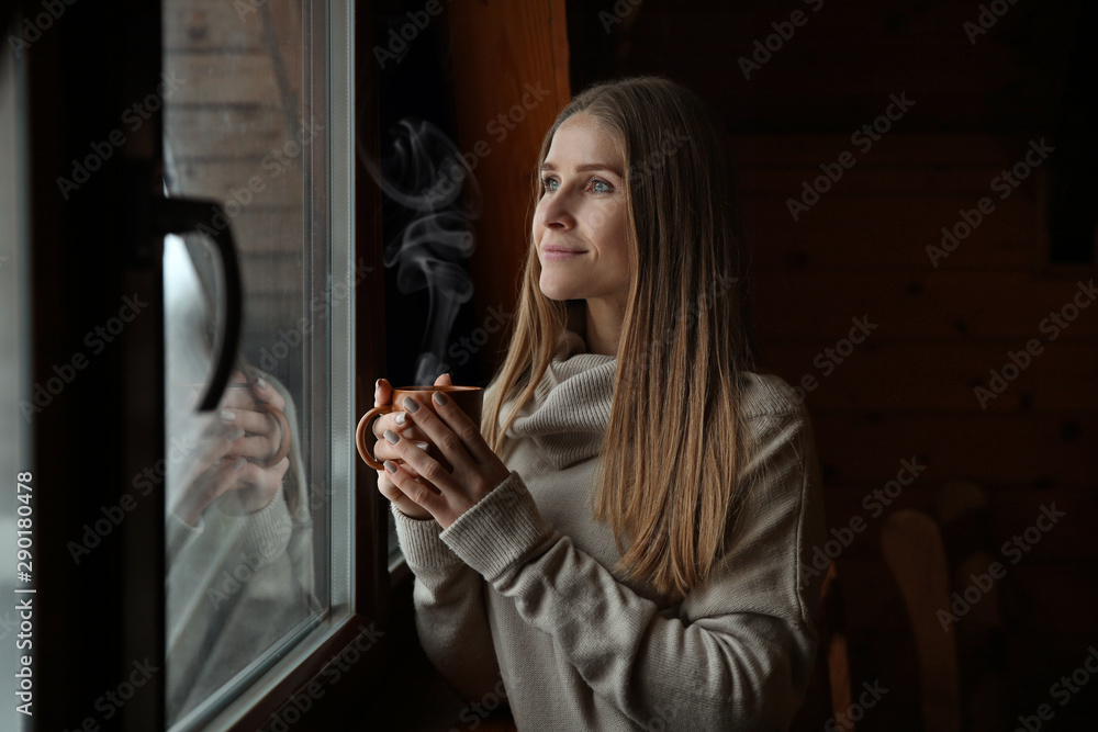 冬日在窗户附近喝热饮的年轻女子