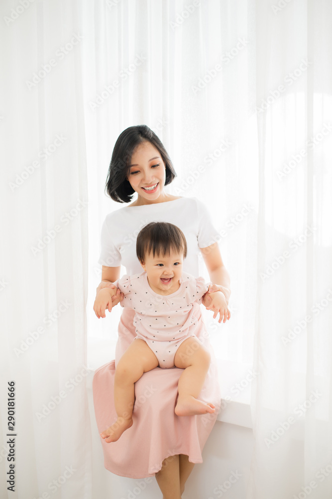 Young mother holding a baby standing in a tulle