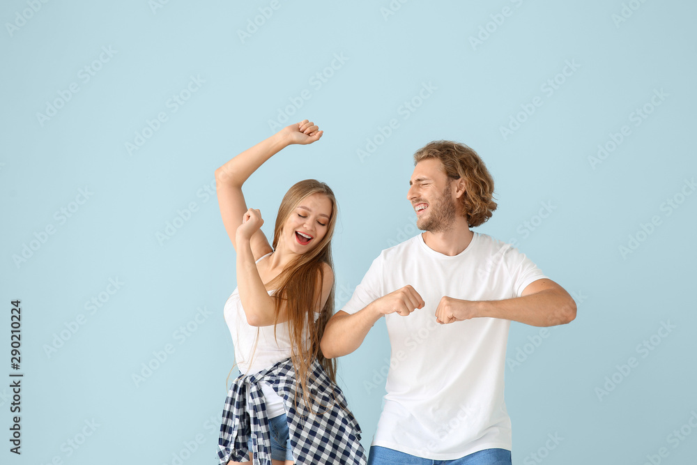 Cool young couple dancing against color background