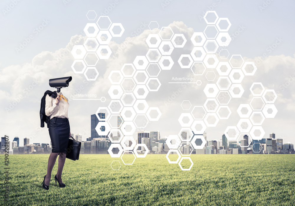 Camera headed woman standing on green grass against modern cityscape