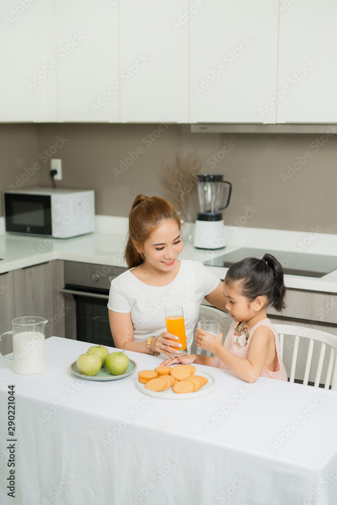 亚洲孩子和她妈妈早上喝橙汁