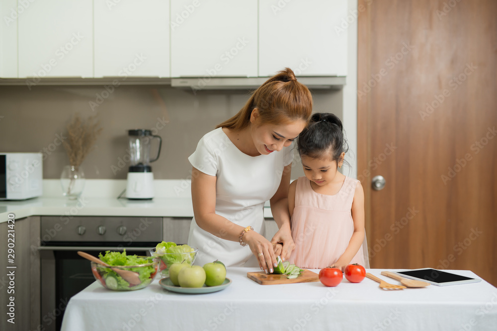 Happy mother and her daughter enjoy making and having healthy meal together at their home