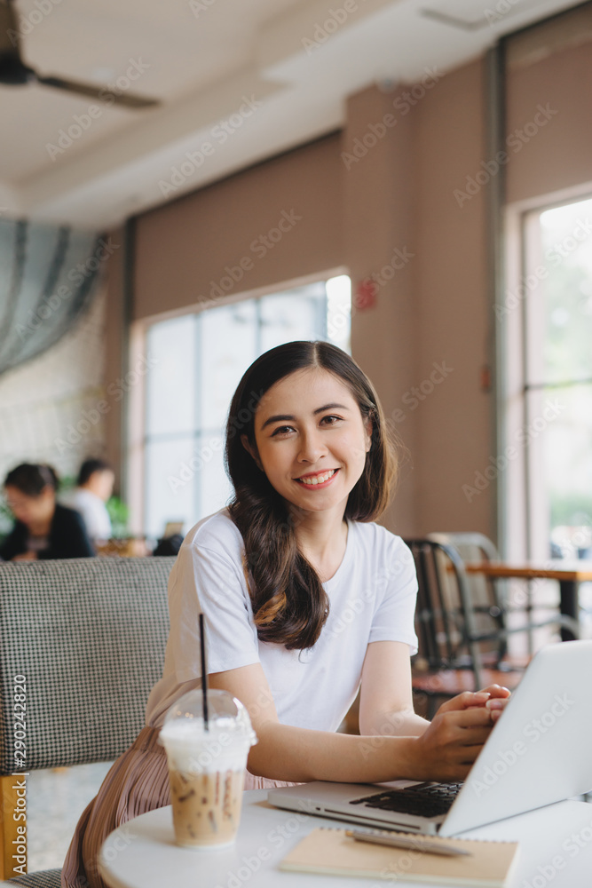 美丽年轻女孩在开放空间的笔记本电脑前工作的生活方式时尚肖像。共同饮酒